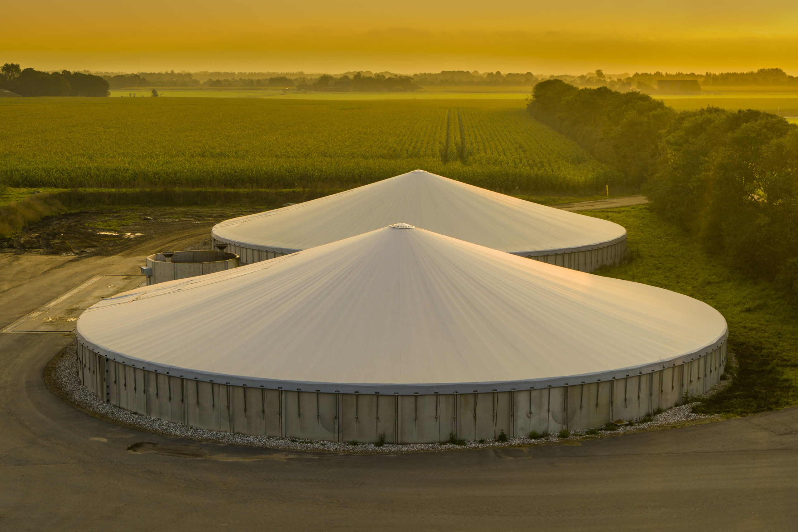 Aerial view of a biogas and biomethane upgrading plant with anaerobic digester tanks surrounded by farmland — BEHG-compliant biomethane production in Europe